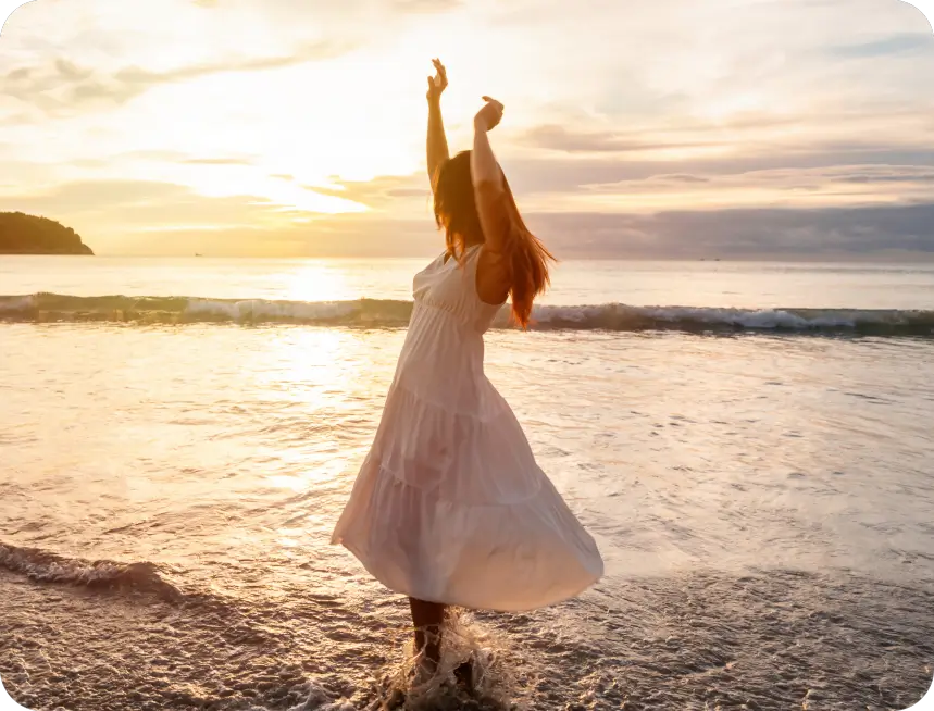 Woman dancing in white dress at sunset.